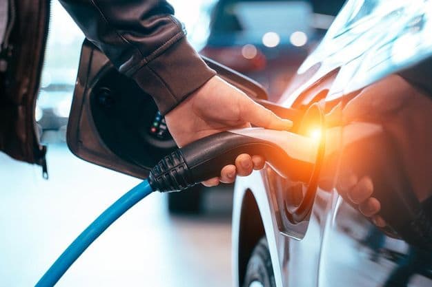 Closes up Human hand is holding Electric Car Charging connect to Electric car