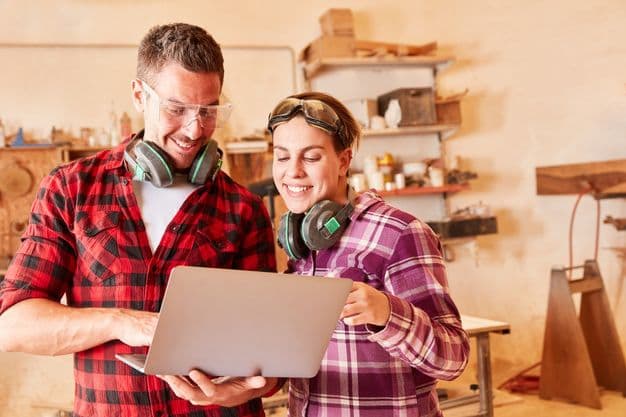 Junge Handwerker schauen zusammen auf einen Laptop Computer in der Werkstatt