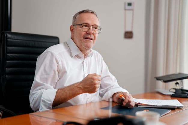 ZDH-Präsident Jörg Dittrich sitzt an einem Schreibtisch und spricht.