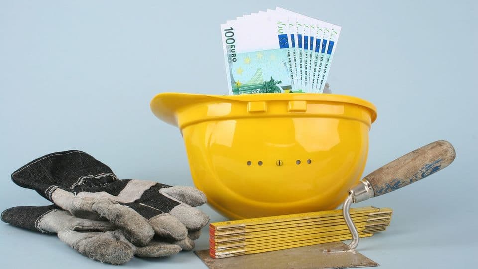 100 Euro-Scheine liegen in einem Bauhelm - mit Werkzeugen daneben.