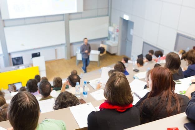 Vorlesung an Uni
Speaker giving presentation in lecture hall at university. Students listening to lecture and making notes.