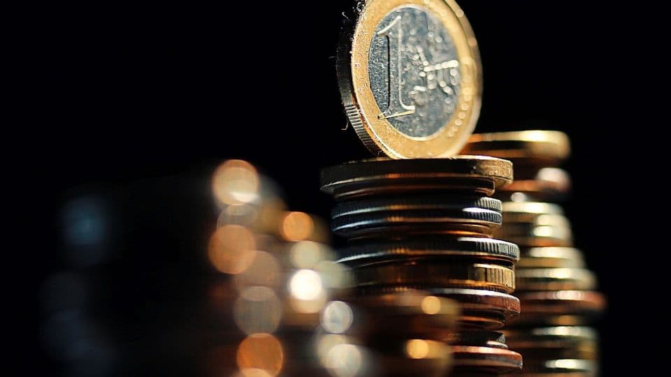 Eine funkelnde 1-Euro-Münze thront auf einem Münzstapel.