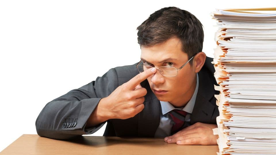 Verwunderter Angestellter am Schreibtisch mit Akten