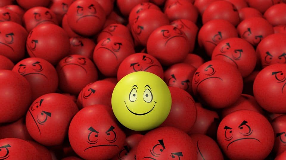 Gelber Smile umringt von verärgerten Gesichtern in Rot