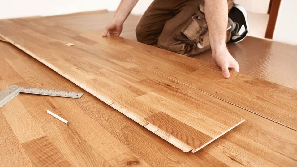 Ein Tischler verlegt Parkett in einer Wohnung.