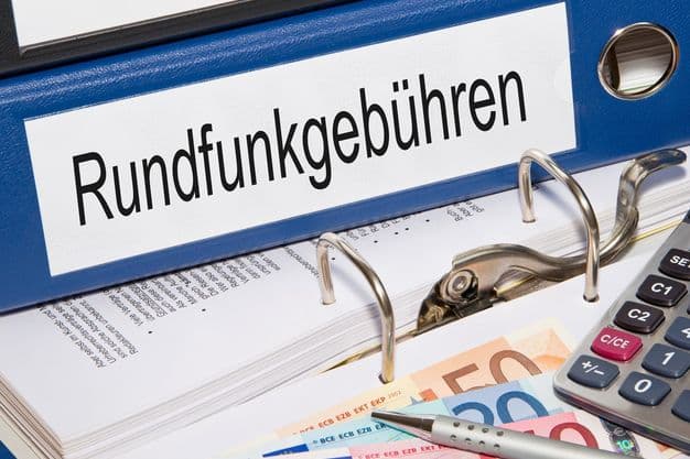 Rundfunkgebühren Ordner liegt auf dem Tisch mit Geldscheinen, Stift und Rechner