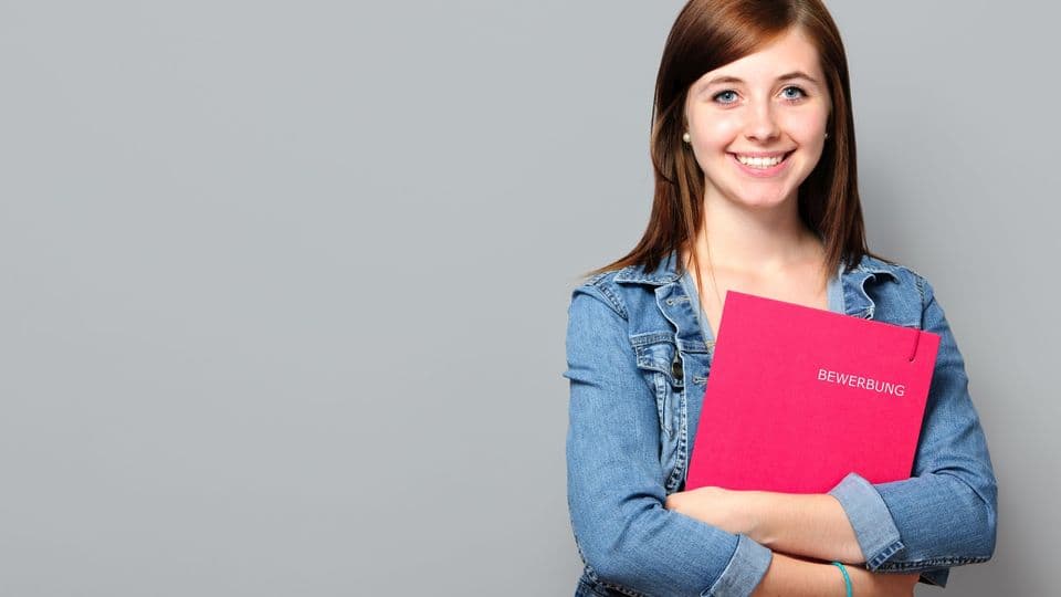 Eine junge Frau hält eine  Bewerbung in den Händen.