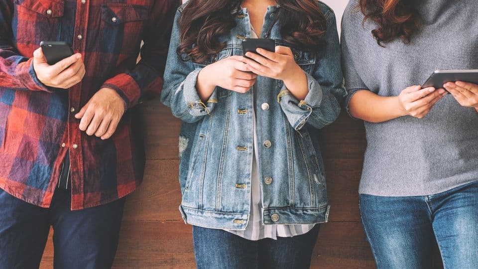 Three young asian people using and looking at mobile phone and tablet pc together