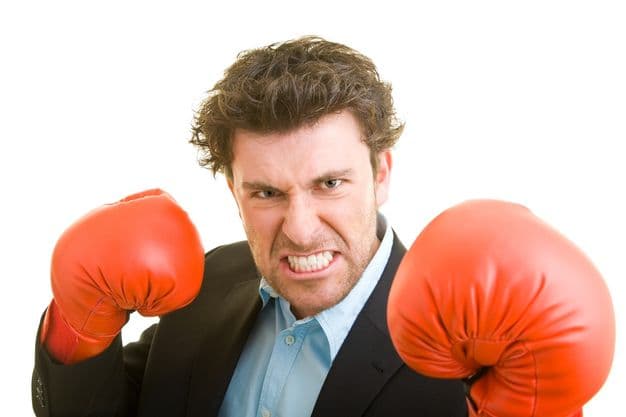 Junger Mann im Anzug mit roten Boxhandschuhen