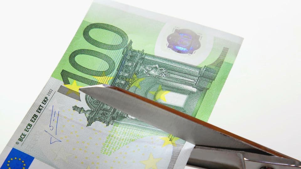 Schere zerschneidet Geldschein