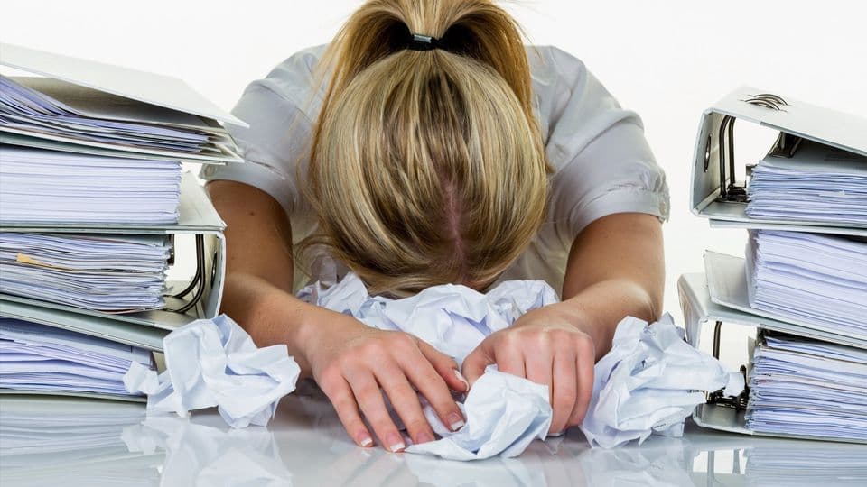 Junge Frau im Büro ist mit der Arbeit überfordert. Burnout bei Arbeit oder Studium.