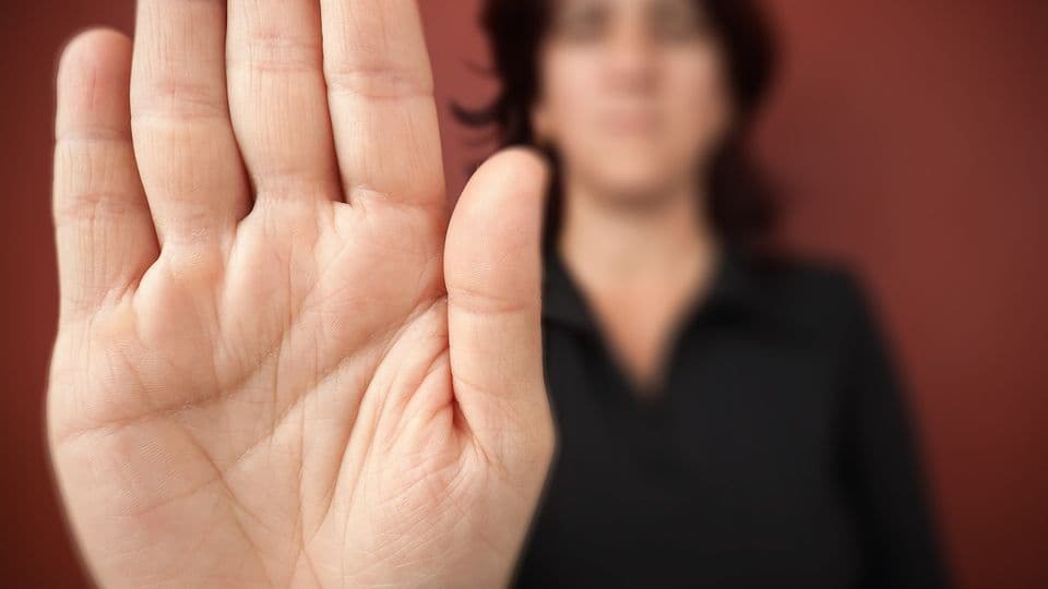 Frau sagt stop
Woman with her hand extended signaling to stop (only her hand is in focus) on a red background