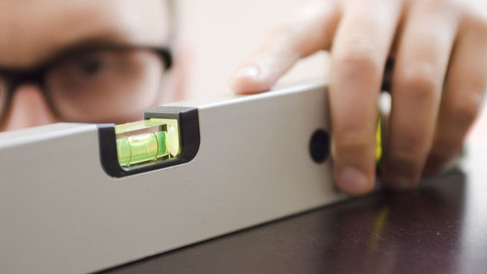 Handwerker prüft vor Baubeginn, ob die Arbeiten des Vorgewerks den Vorgaben des Bauherrn entsprechen.