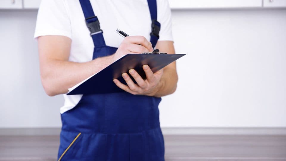 handwerker im blaumann mit auftragsschein
Plumber in uniform holding clipboard at kitchen