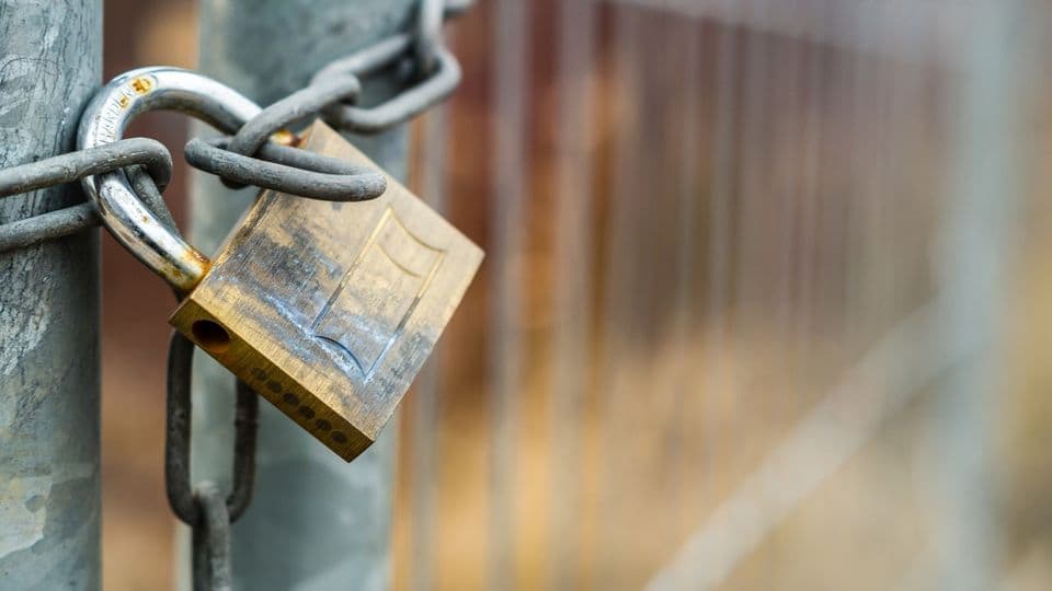 Bauzaun mit Vorhängeschloss verschlossen.