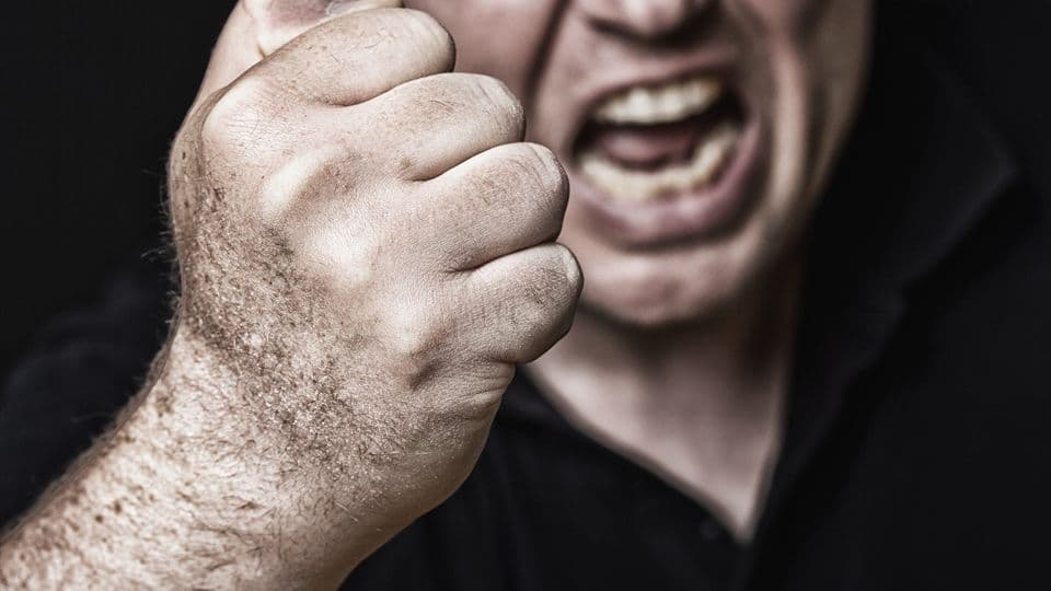 Ein Mann hebt aggressiv drohend die Faust.