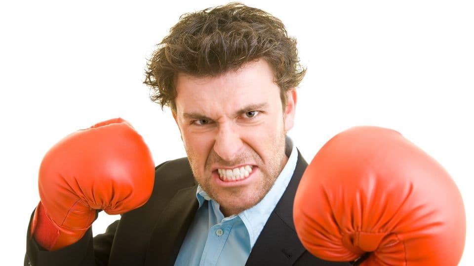 Junger Mann im Anzug mit roten Boxhandschuhen